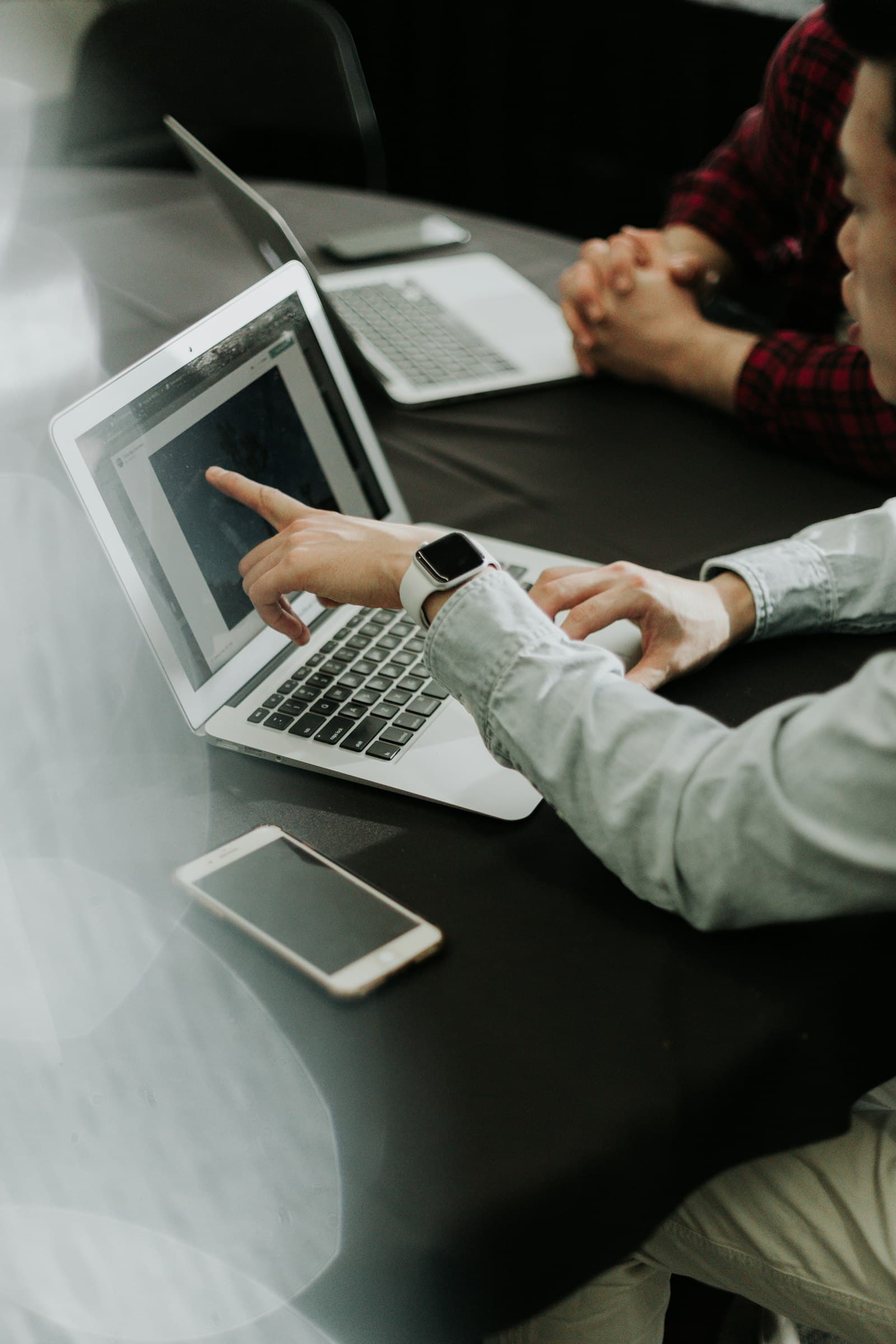 Two people pointing at a laptop screen in a meeting